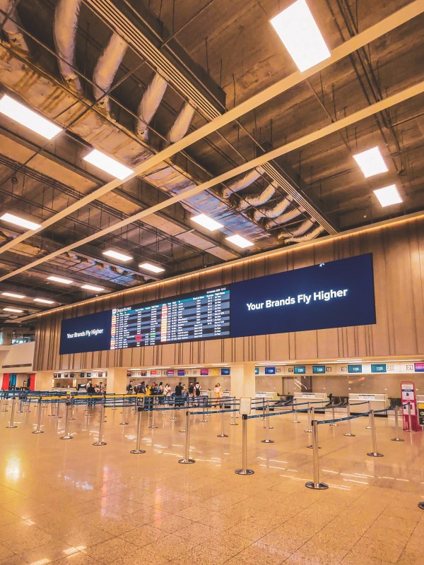 Airport check-in desks beneath departure information screens.