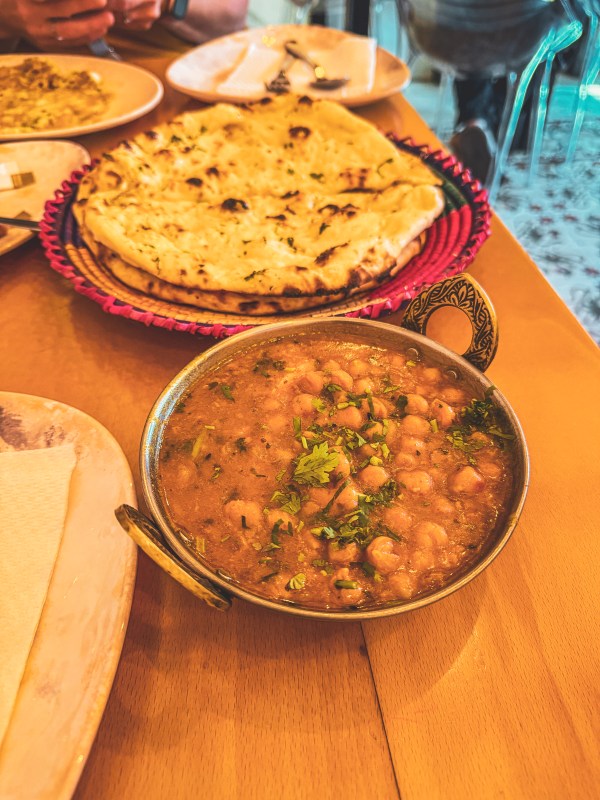 A curry and flatbread served on a wooden restaurant table.