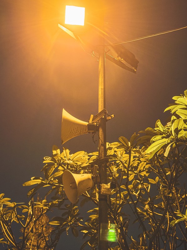 A streetlamp glowing above foliage at night in Hanoi.