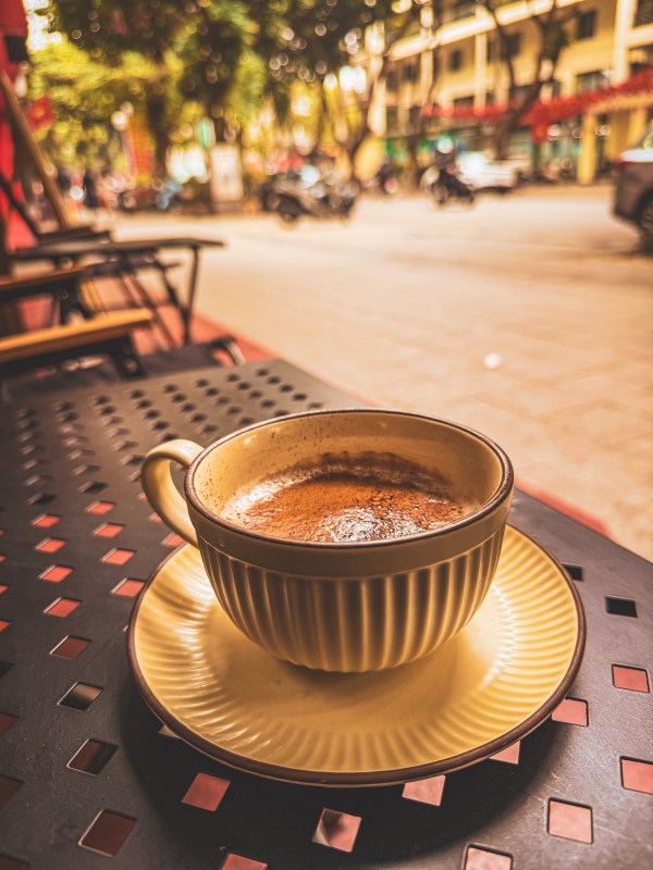 A cup of coffee on a café table beside a Hanoi street.