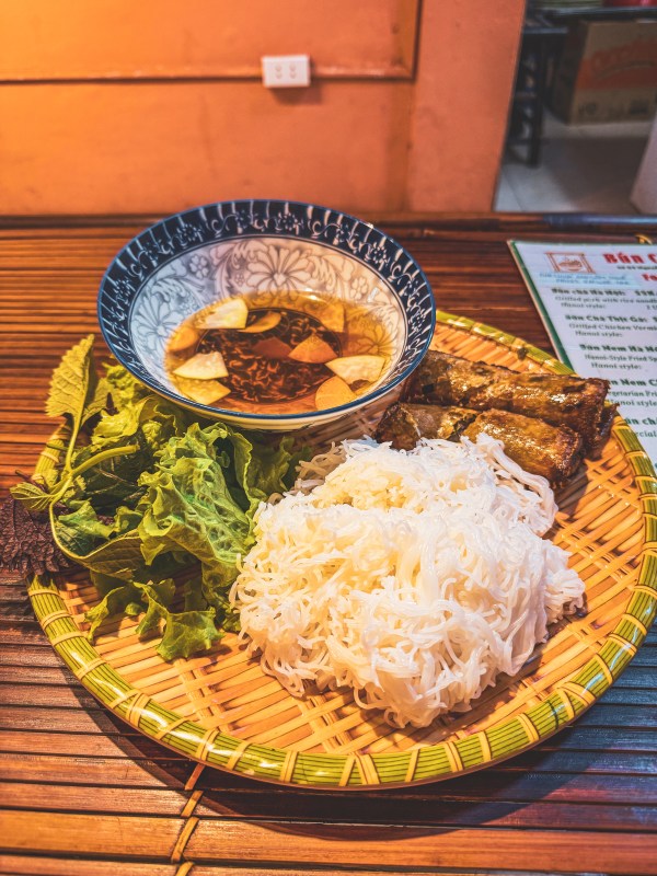 A platter of food with herbs and noodles on a Hanoi table.