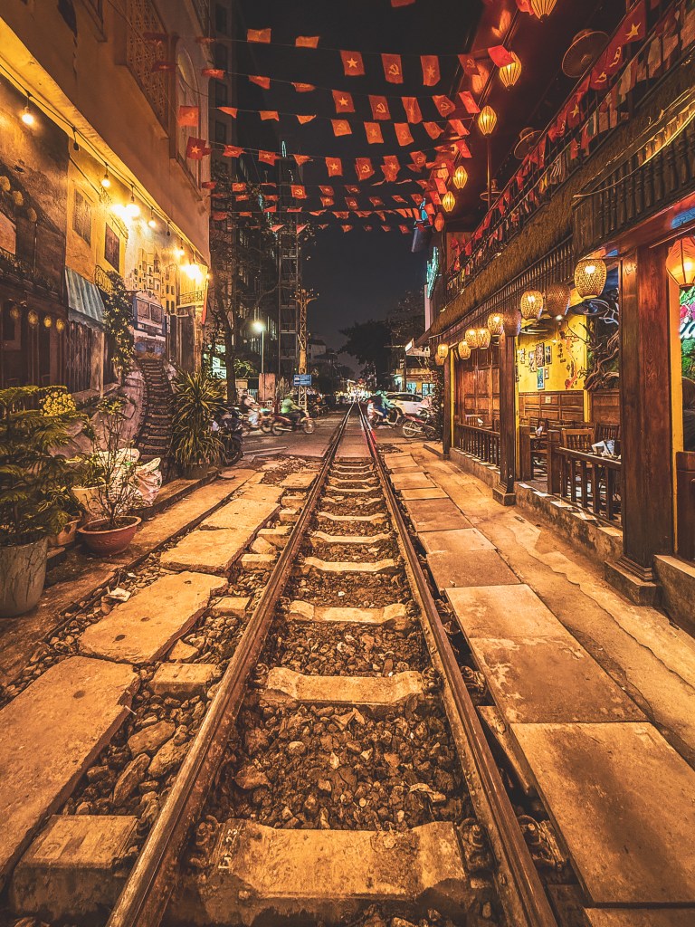Lanterns and lights beside Hanoi’s railway street at night.
