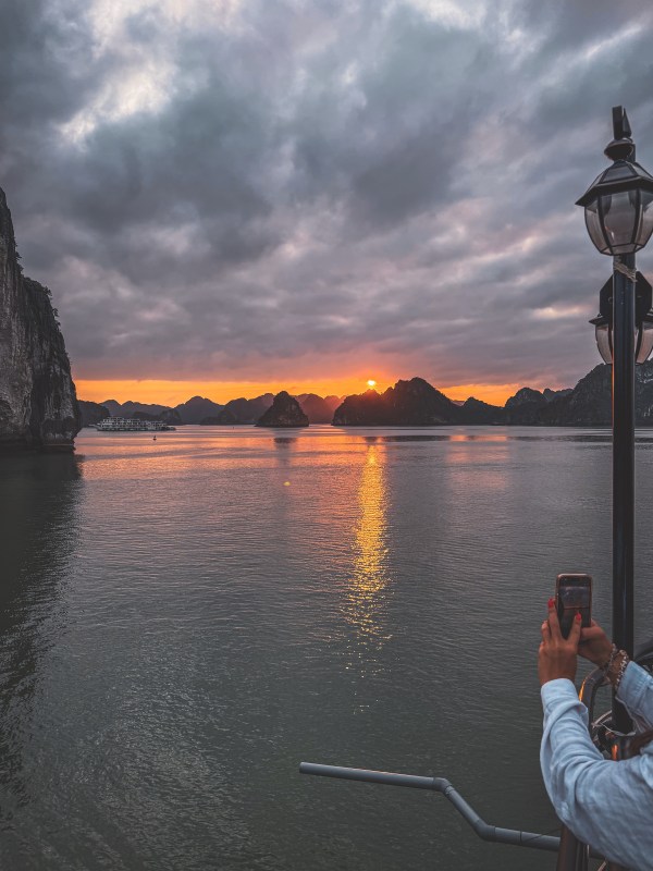 Water and distant rocky silhouettes beneath a sunset sky in Vietnam.