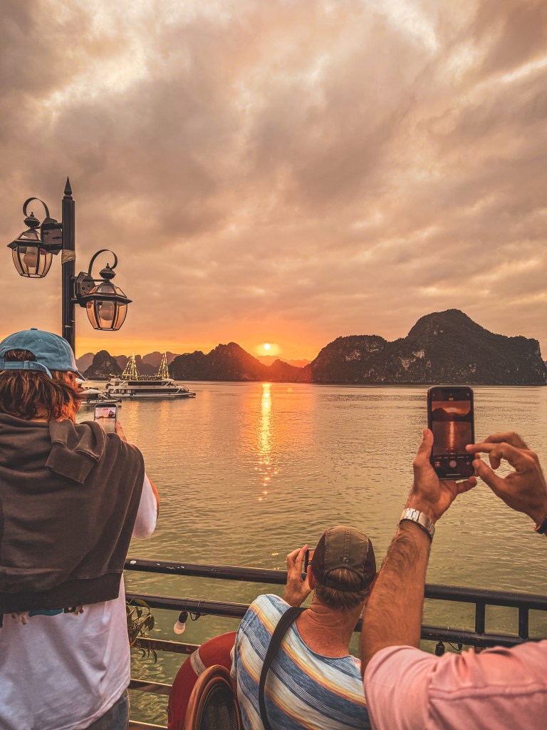 Travellers on a boat beneath a golden sunset in Vietnam.