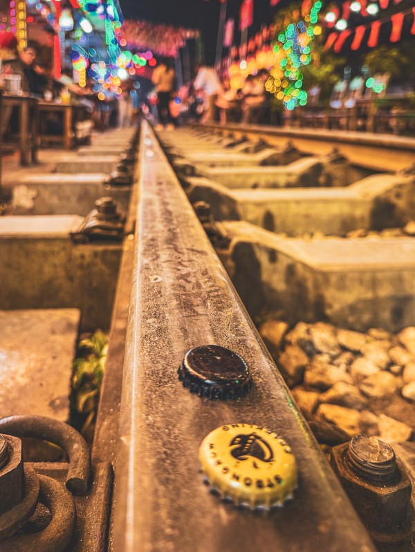 Close view along a Hanoi rail with bottle caps and lights beyond.