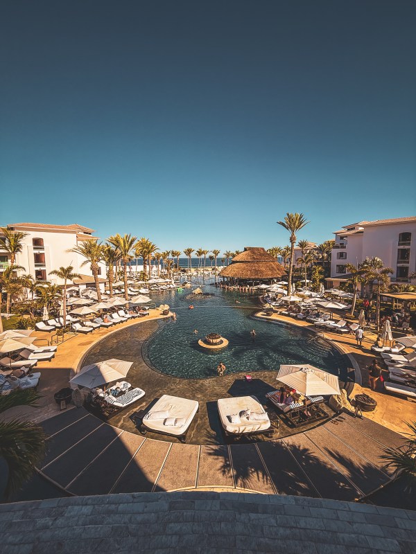 An elevated view across a resort pool and surrounding buildings.