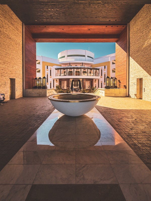 A resort courtyard framed by a covered passage, with a central water feature.