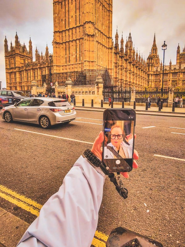 A smartphone displaying its front camera outside the Palace of Westminster in London.