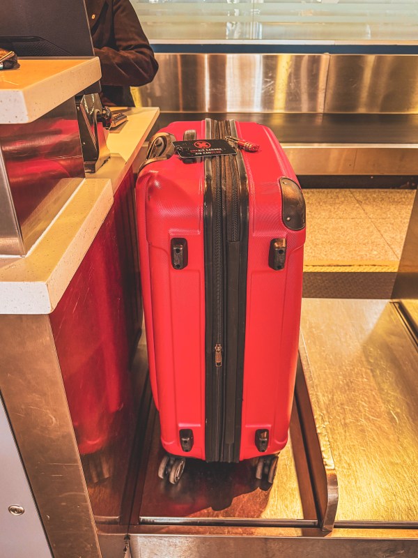 A red hard-shell suitcase beside a counter.