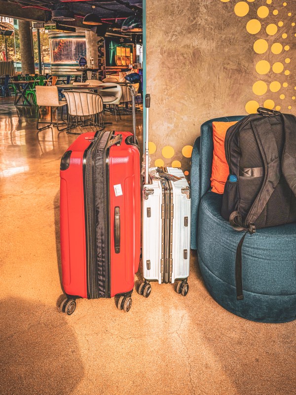 Several suitcases and a backpack together in an indoor travel space.