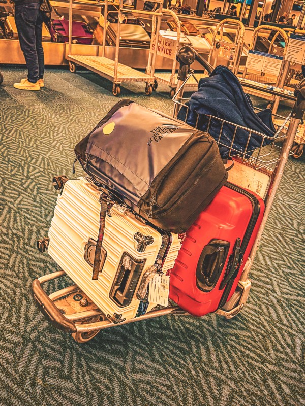 Luggage piled on a trolley in an airport-style waiting area.
