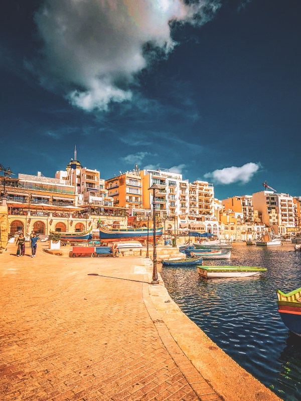 A waterfront lined with stone buildings and boats in Malta.