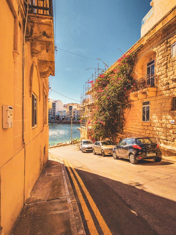 Sunlit Malta street leading toward the waterfront.