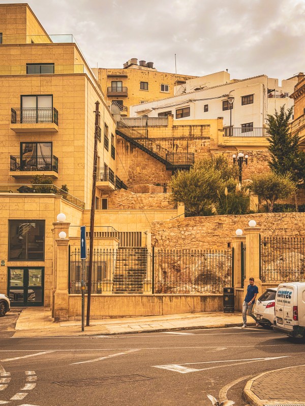 Stone buildings and balconies above a street in Malta.