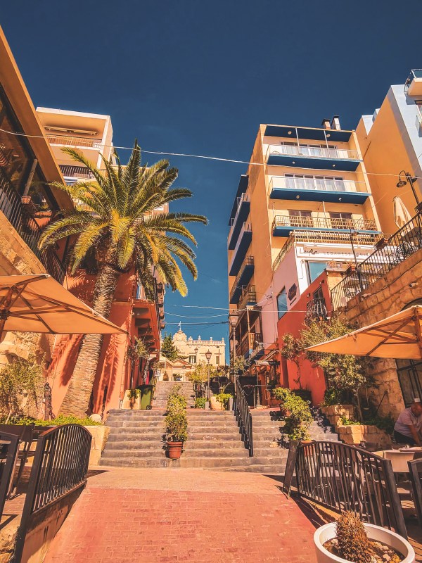 A stepped passage with palms and outdoor umbrellas in Malta.