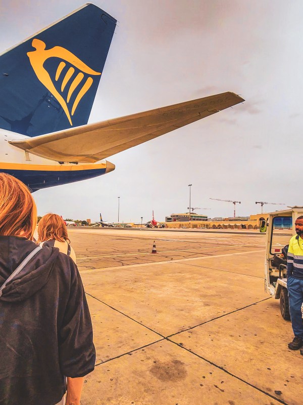 Travellers boarding beside a Ryanair aircraft wing in Malta.