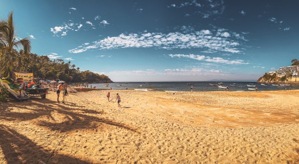 A sandy beach beside palms and the sea in Mismaloya, Mexico.