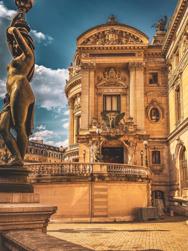 An ornate Paris façade with a sculpture in the foreground.