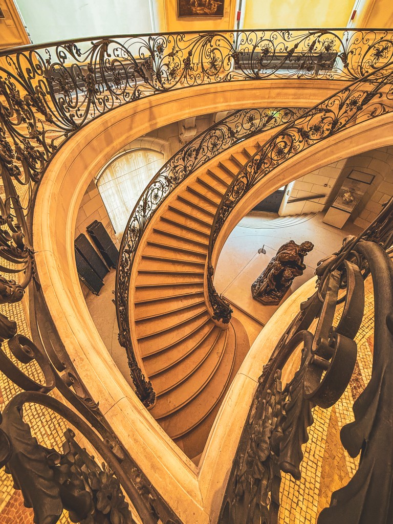 An ornate curved staircase inside a Paris building.