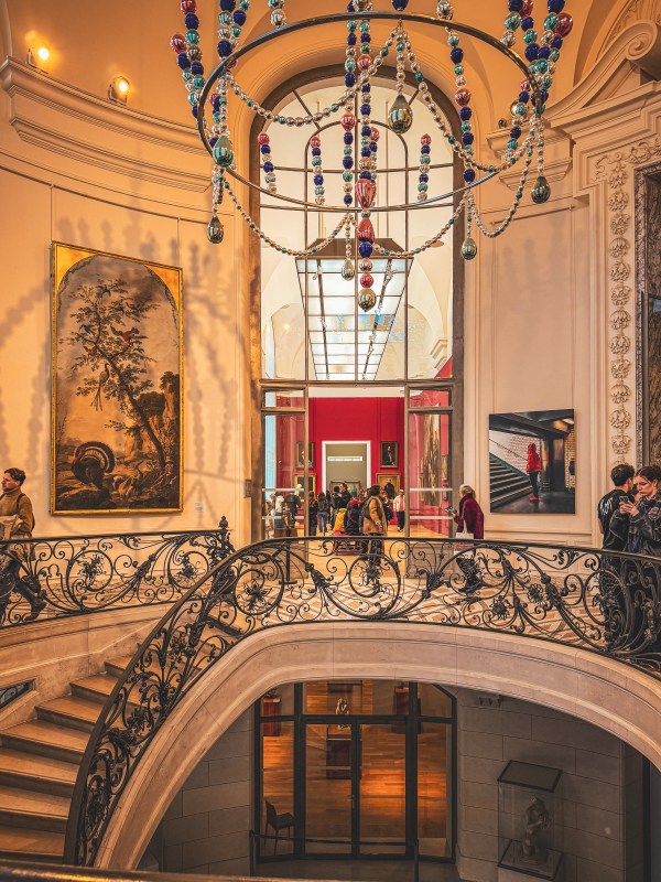 An ornate Paris interior with curved railings and a hanging installation.