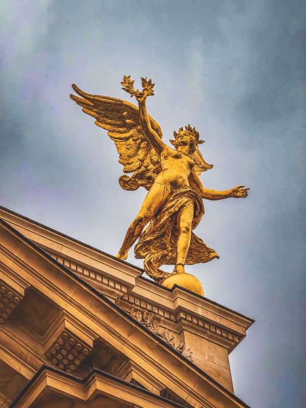 A golden winged sculpture above an ornate Paris building.