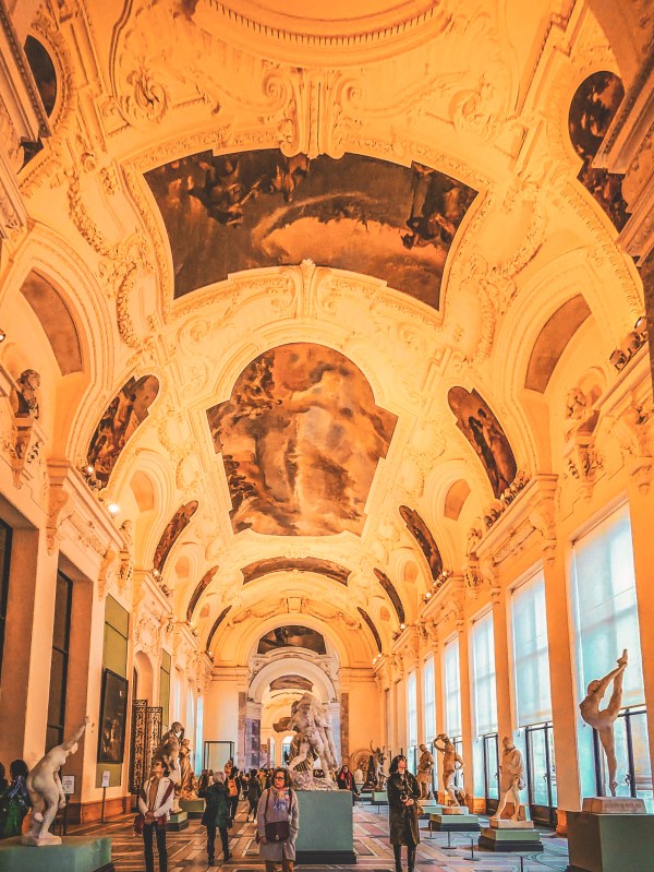 An ornate Paris interior with ceiling paintings and tall windows.