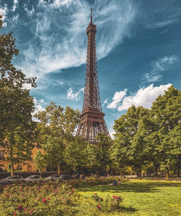 The Eiffel Tower framed by trees and a garden in Paris.