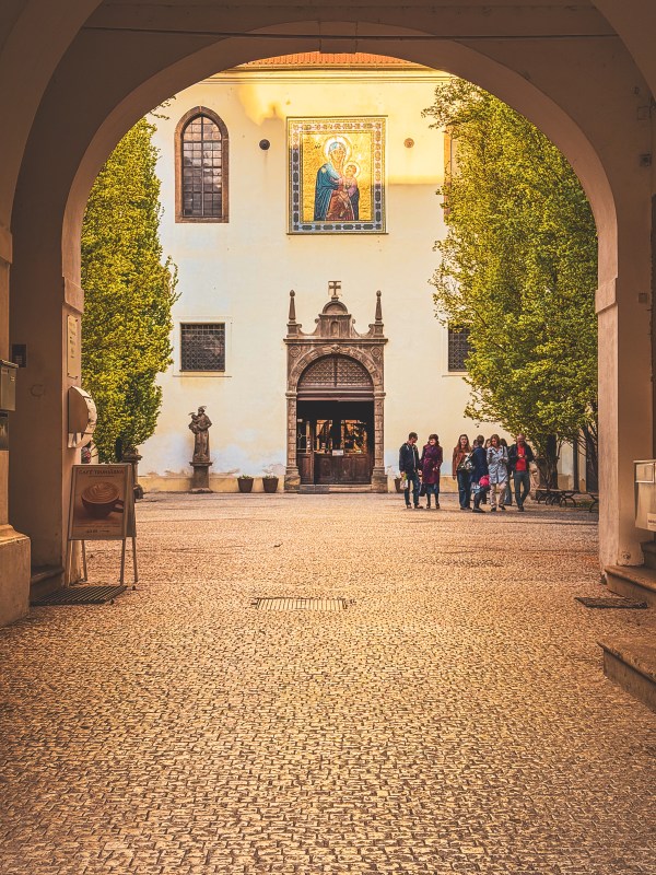 A courtyard and building framed by an archway in Prague.