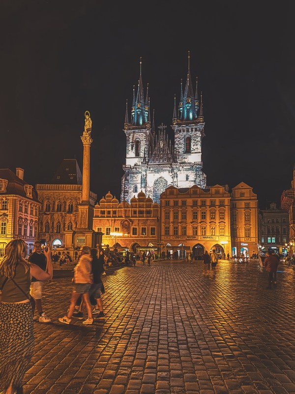 An illuminated church above a Prague square at night.