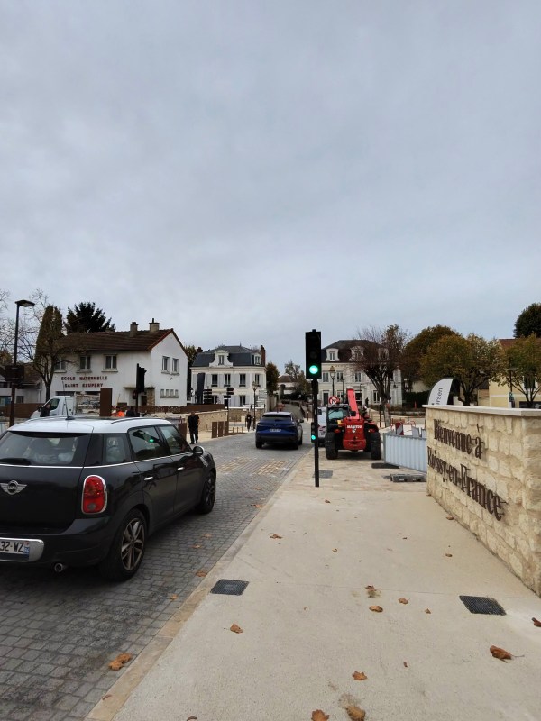 A street with parked cars and buildings in Roissy-en-France.