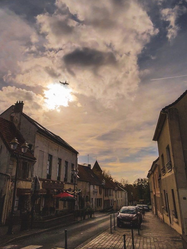 A Roissy-en-France street beneath a bright cloudy sky.