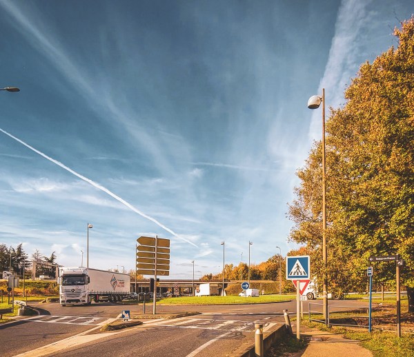 A road and signs beneath a broad blue sky near Roissy-en-France.