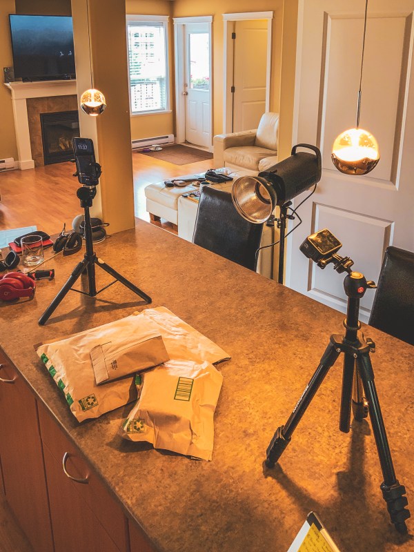 A smartphone, tripod and filming equipment arranged on a tabletop.