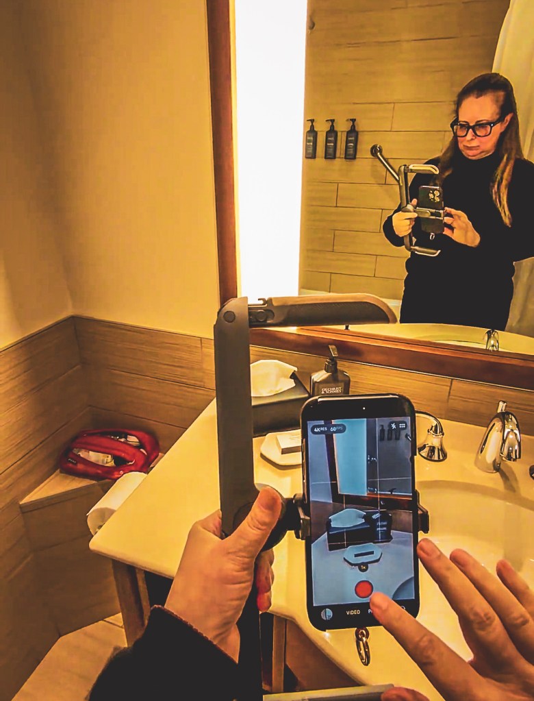 A creator films a mirror shot with a smartphone and handheld stabilizer.