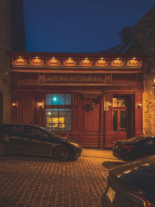 Warmly lit brick building on a cobbled street at night.