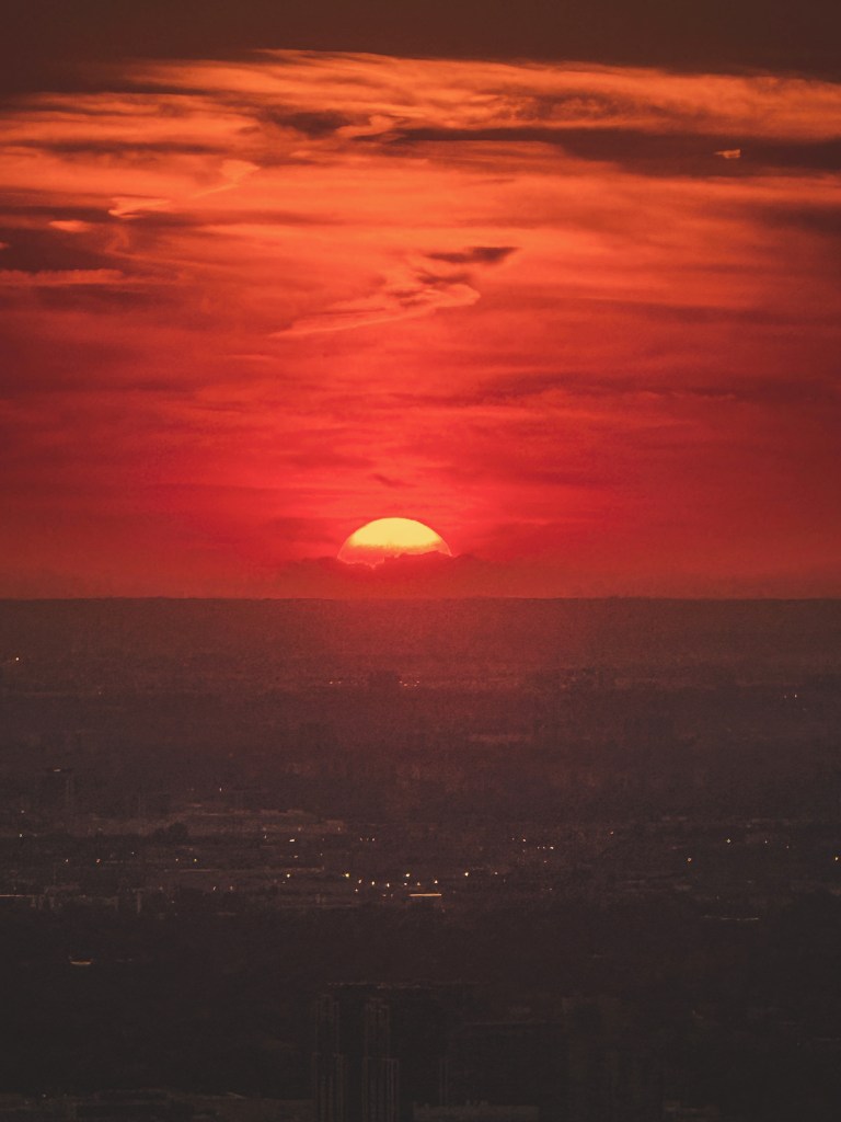 A vivid sunset above silhouetted trees in Canada.
