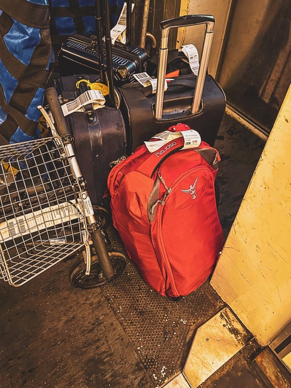 Suitcases and red backpack loaded on a luggage trolley.