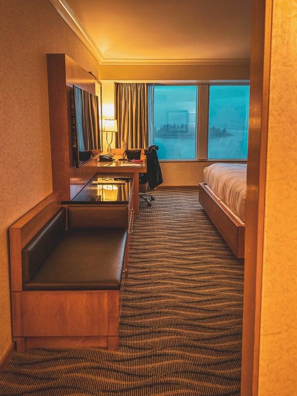 Hotel room with bed, desk and large window.