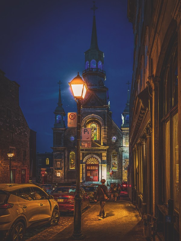 Illuminated clock tower on a city street at night.