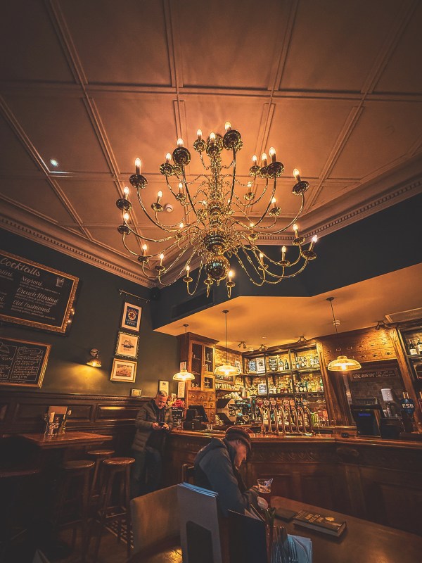 Chandelier above a warmly lit London dining room.