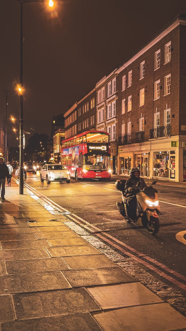 London street with traffic and a red bus at night.