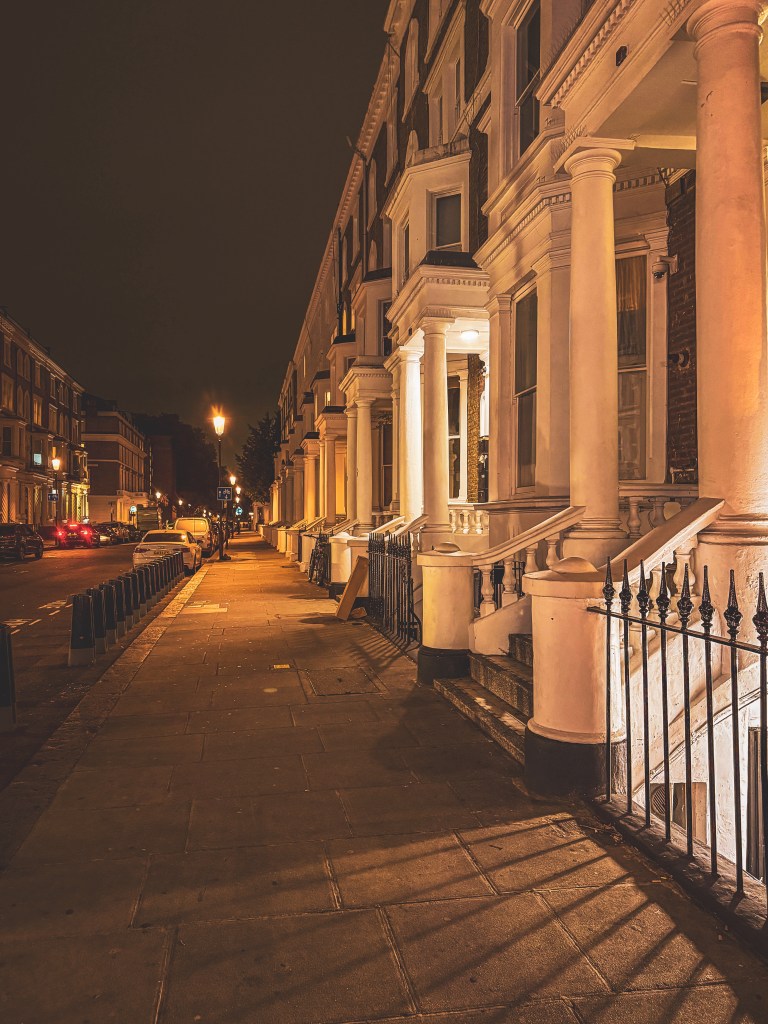 Residential terraces and pavement in London at night.
