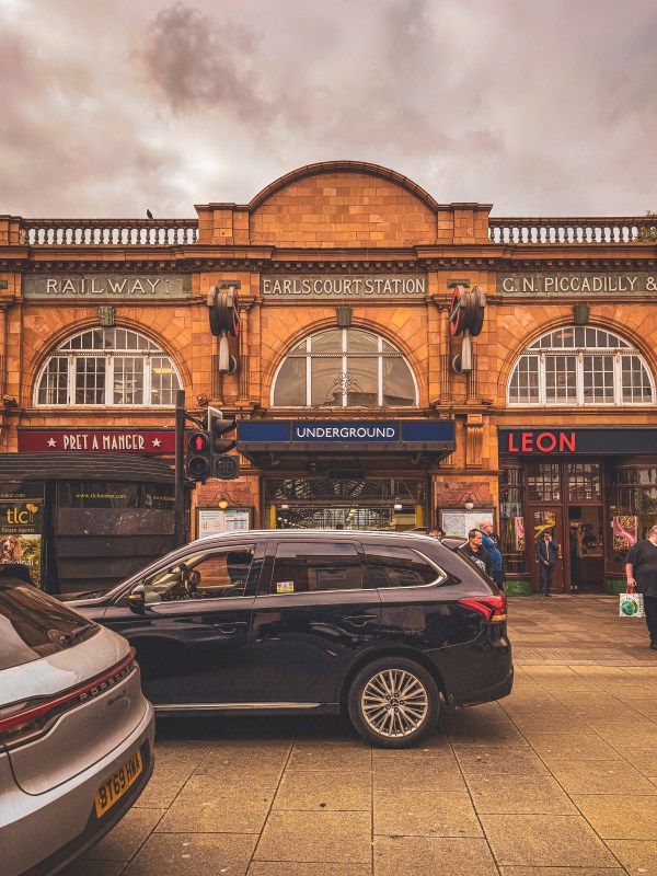 Black taxi outside a brick-fronted London building.
