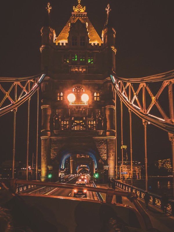 Illuminated Tower Bridge seen along its pedestrian walkway at night.