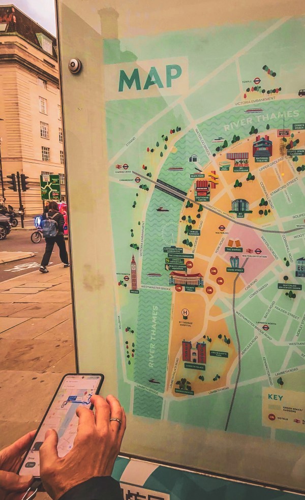 A traveller uses a smartphone beside a London map.